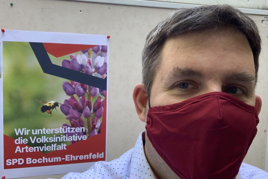 Jens Matheuszik vor dem Plakat "Wir unterstützen die Volksinitiative Artenvielfalt" (SPD Bochum-Ehrenfeld)