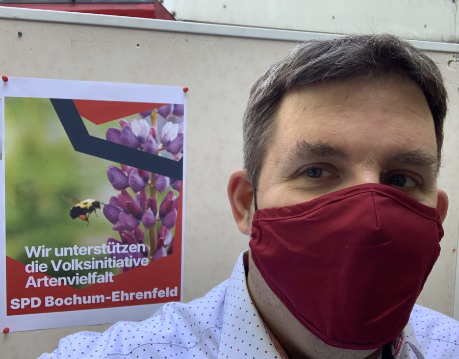Jens Matheuszik vor dem Plakat "Wir unterstützen die Volksinitiative Artenvielfalt" (SPD Bochum-Ehrenfeld)